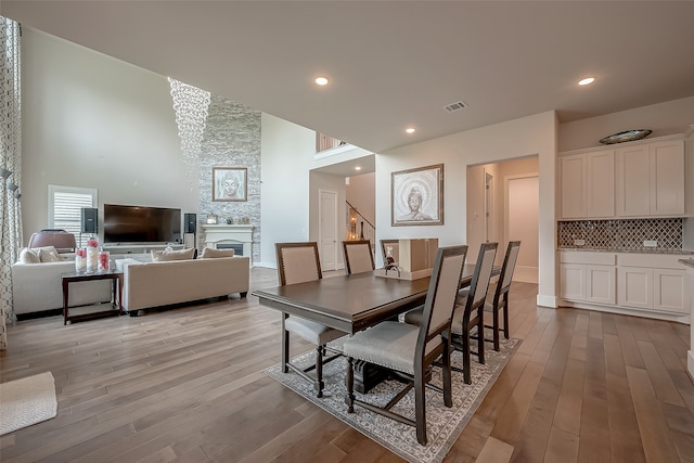 dining area with a fireplace, a towering ceiling, and light hardwood / wood-style flooring