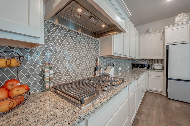 kitchen with white cabinets, premium range hood, white refrigerator, and light wood-type flooring