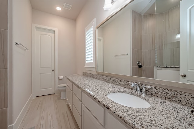 bathroom with walk in shower, vanity, and toilet