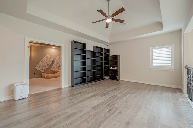 unfurnished bedroom with light hardwood / wood-style floors and a raised ceiling