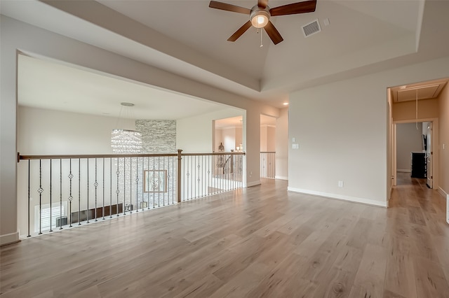 empty room with ceiling fan with notable chandelier and light wood-type flooring