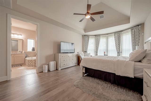 bedroom with light wood-type flooring, ensuite bath, multiple windows, and ceiling fan