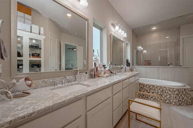 bathroom featuring tiled bath, vanity, and ceiling fan