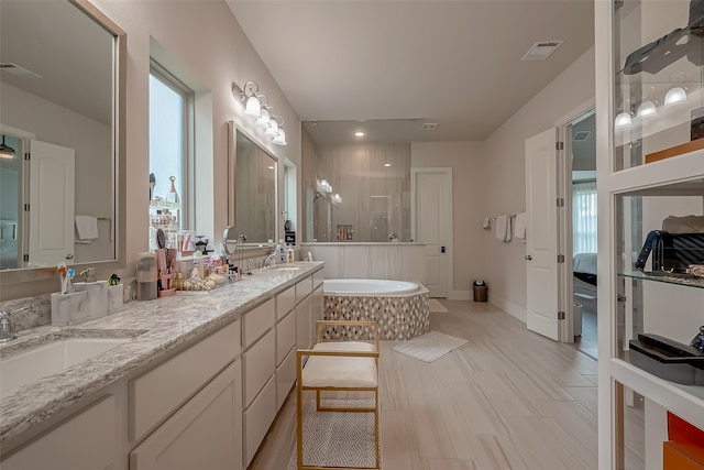 bathroom with vanity, a bath, and a healthy amount of sunlight