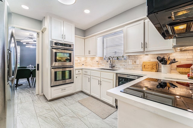 kitchen with decorative backsplash, a wealth of natural light, stainless steel appliances, sink, and white cabinetry