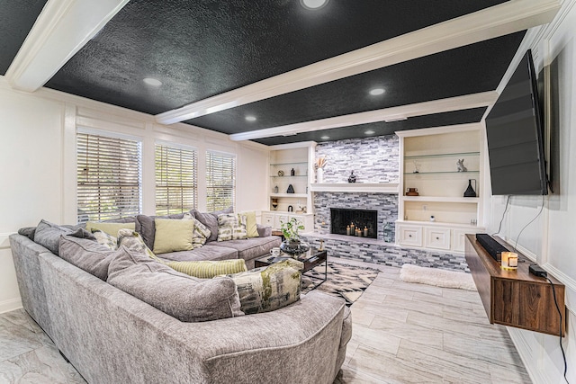 living room featuring beam ceiling, built in shelves, crown molding, and a stone fireplace