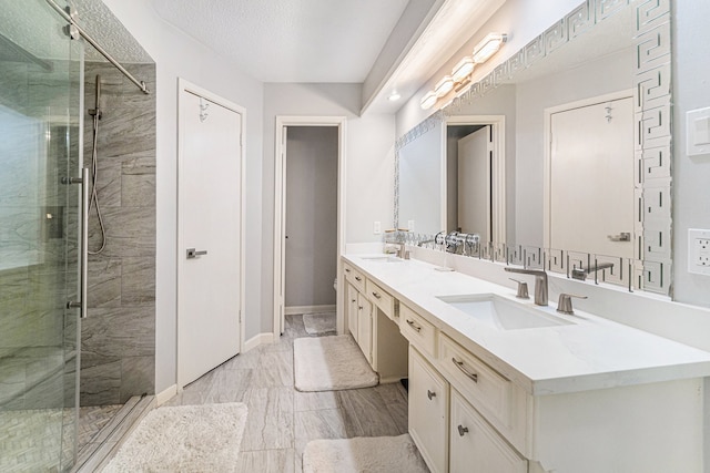 bathroom with a textured ceiling, vanity, and a shower with door