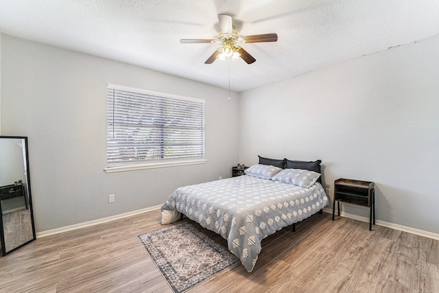 bedroom with ceiling fan, light hardwood / wood-style floors, and a textured ceiling