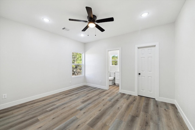 unfurnished bedroom with hardwood / wood-style floors, ceiling fan, connected bathroom, and a closet