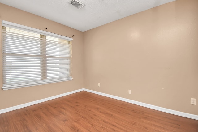 unfurnished room with a textured ceiling, wood-type flooring, and plenty of natural light