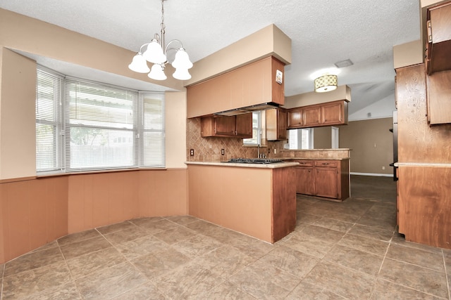 kitchen with kitchen peninsula, light tile patterned floors, a notable chandelier, pendant lighting, and decorative backsplash