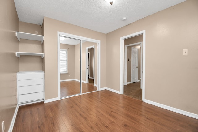 unfurnished bedroom featuring a closet, a textured ceiling, and dark hardwood / wood-style floors