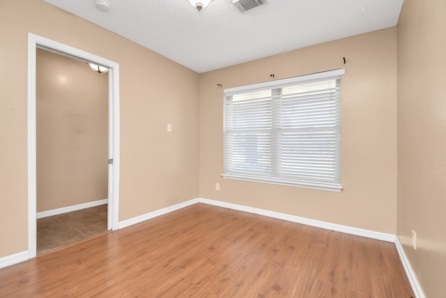 empty room with a textured ceiling and hardwood / wood-style flooring