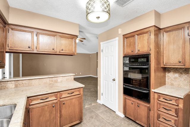 kitchen with light tile patterned flooring, a textured ceiling, light stone counters, and decorative backsplash