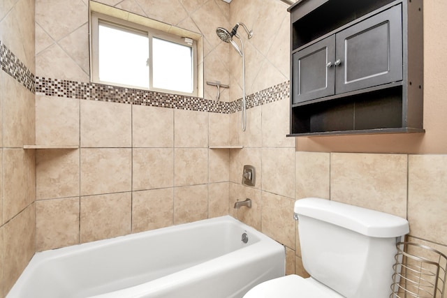 bathroom with tiled shower / bath, toilet, and tile walls