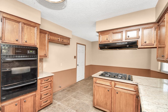 kitchen featuring light tile patterned flooring, stainless steel gas cooktop, a textured ceiling, and double oven