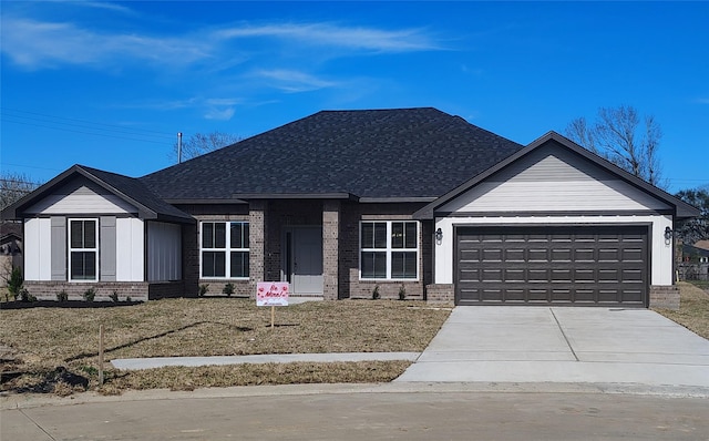 view of front facade featuring concrete driveway, an attached garage, brick siding, and roof with shingles