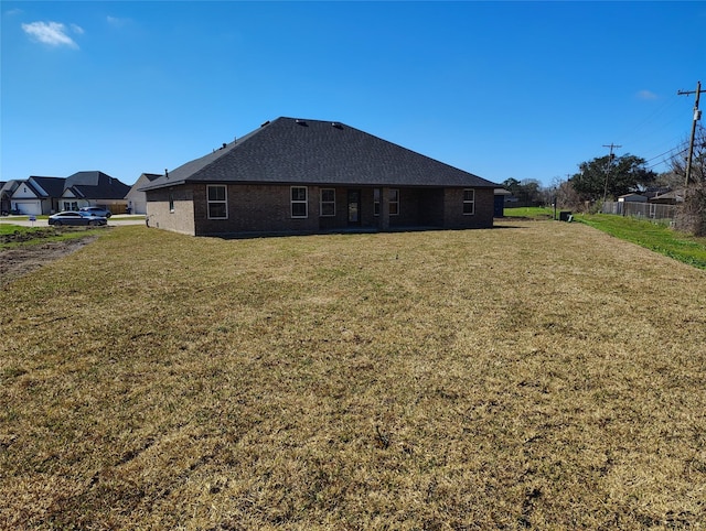 rear view of property featuring brick siding and a lawn