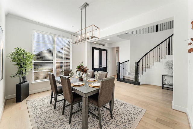 dining room featuring ornamental molding, french doors, light hardwood / wood-style floors, and a chandelier