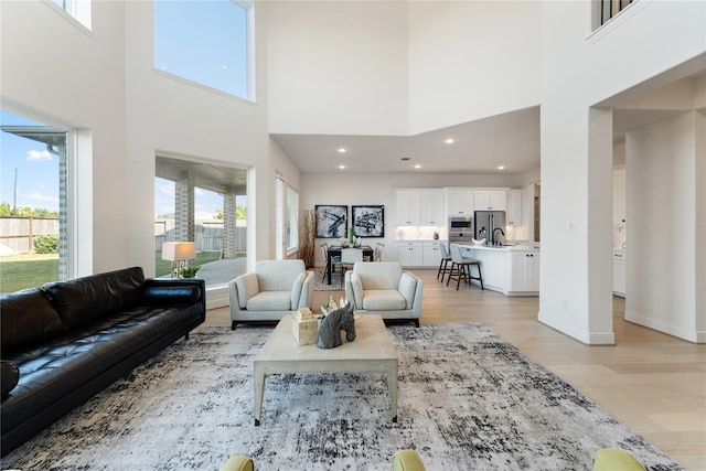 living room with a towering ceiling, a healthy amount of sunlight, and light wood-type flooring