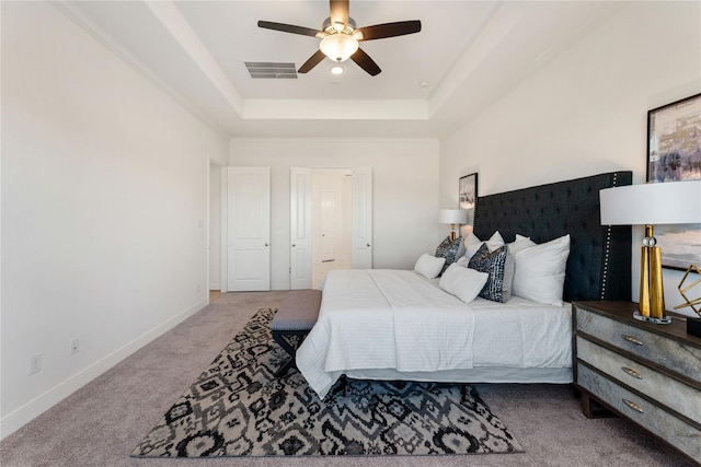 bedroom featuring ceiling fan, a raised ceiling, and light colored carpet