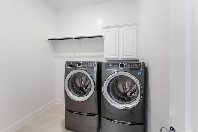 laundry area featuring cabinets, light tile patterned flooring, and independent washer and dryer