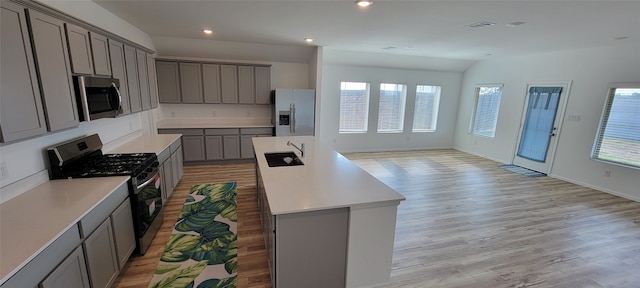 kitchen with gray cabinetry, a healthy amount of sunlight, stainless steel appliances, and light hardwood / wood-style floors