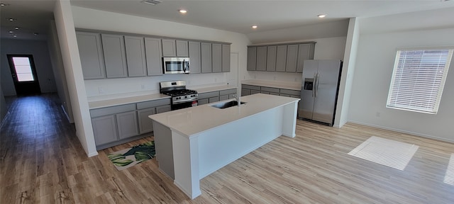 kitchen featuring sink, stainless steel appliances, a center island with sink, and light hardwood / wood-style floors