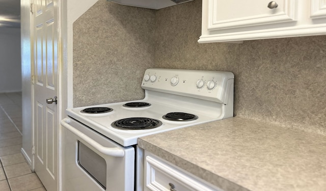 kitchen with electric stove, white cabinets, light tile patterned flooring, and ventilation hood