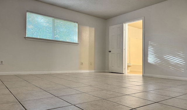 tiled empty room featuring a textured ceiling