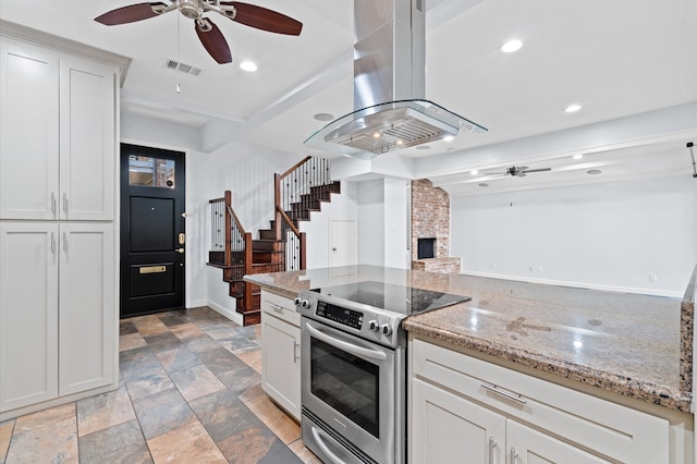 kitchen with white cabinets, stainless steel electric stove, light stone countertops, and island range hood