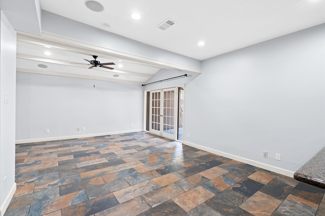 empty room with beamed ceiling, a barn door, and ceiling fan