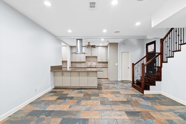 kitchen with tasteful backsplash, sink, white cabinets, kitchen peninsula, and wall chimney exhaust hood