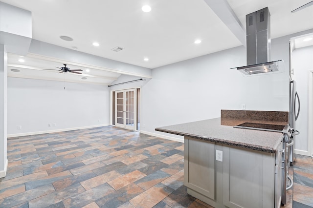 kitchen with ceiling fan, dark stone countertops, island range hood, stainless steel range with electric cooktop, and gray cabinetry