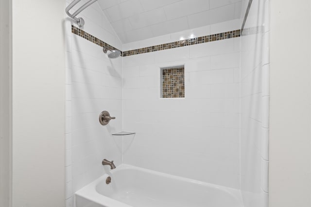 bathroom featuring lofted ceiling and tiled shower / bath combo