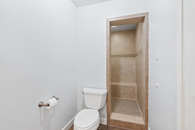 bathroom with toilet, tile patterned floors, and a tile shower