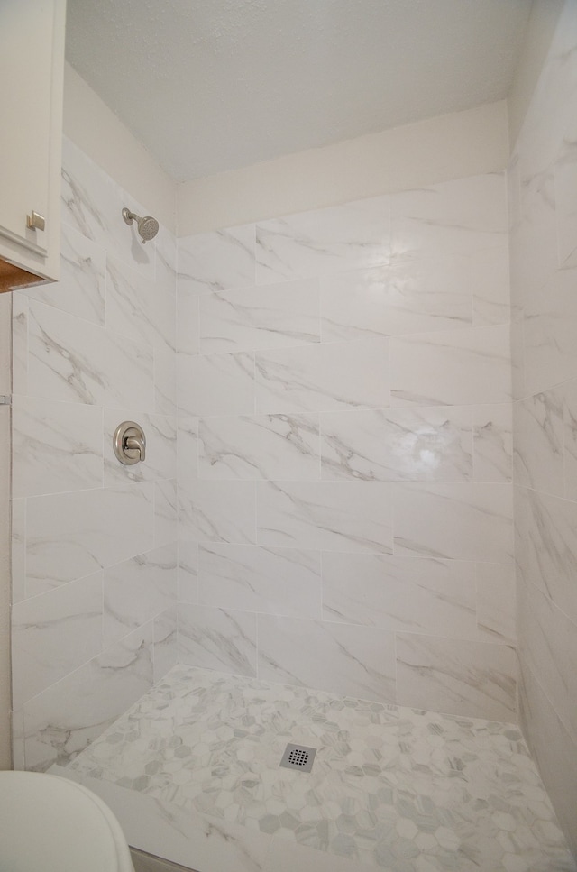 bathroom featuring toilet and tiled shower