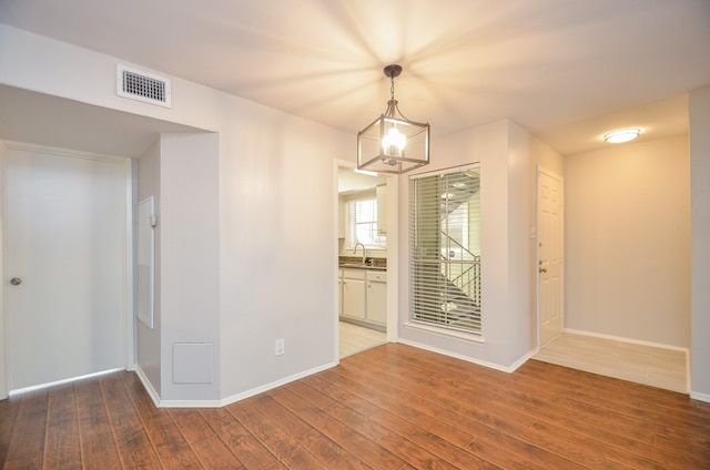 unfurnished room featuring a chandelier, wood-type flooring, and sink