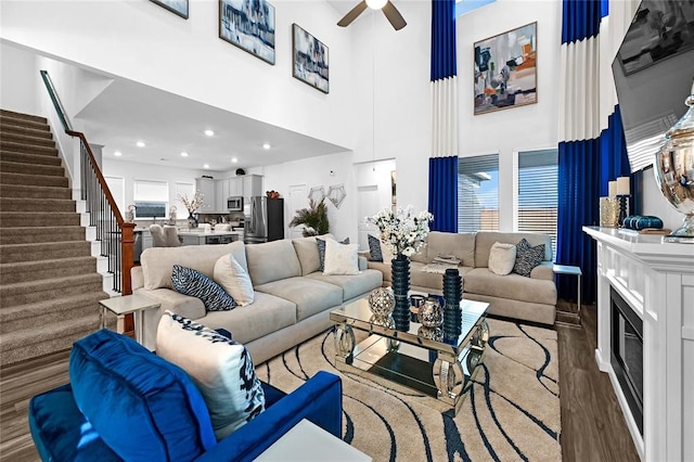 living room featuring hardwood / wood-style floors, a towering ceiling, and ceiling fan