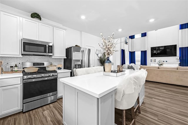 kitchen with tasteful backsplash, white cabinetry, a center island, and appliances with stainless steel finishes