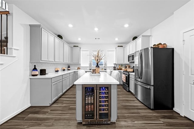 kitchen featuring dark wood-type flooring, stainless steel appliances, tasteful backsplash, wine cooler, and a kitchen island