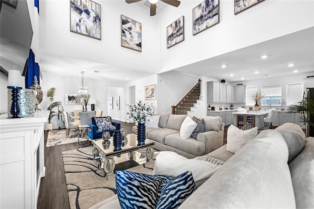 living room with hardwood / wood-style flooring, ceiling fan, and a high ceiling