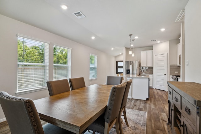 dining room with dark wood-type flooring, sink, and vaulted ceiling