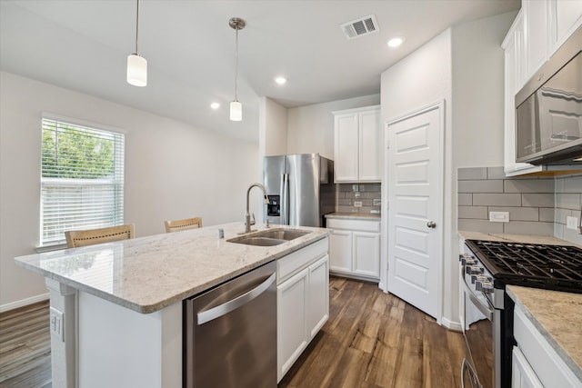 kitchen with a center island with sink, white cabinetry, appliances with stainless steel finishes, hanging light fixtures, and sink