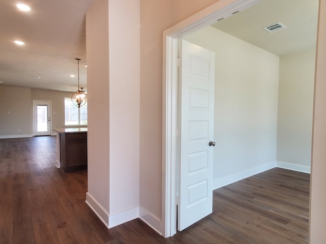 hallway with visible vents, baseboards, and dark wood-style flooring