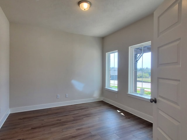 spare room featuring dark wood finished floors and baseboards