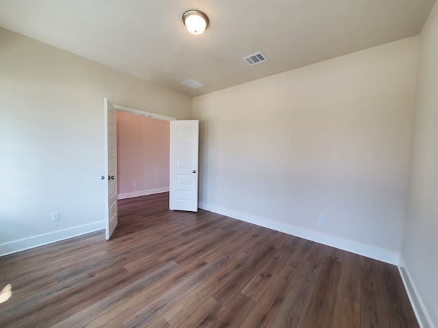 unfurnished room with visible vents, dark wood-type flooring, and baseboards