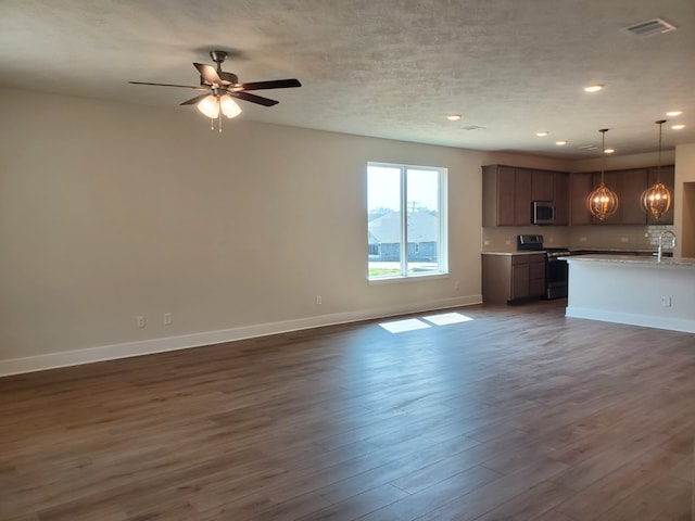 unfurnished living room with visible vents, dark wood-type flooring, baseboards, recessed lighting, and a sink