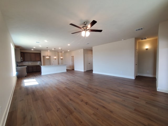 unfurnished living room with visible vents, baseboards, dark wood-type flooring, and a ceiling fan