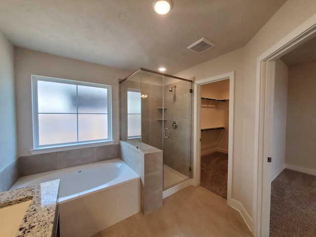 full bathroom with baseboards, visible vents, a stall shower, a spacious closet, and a bath